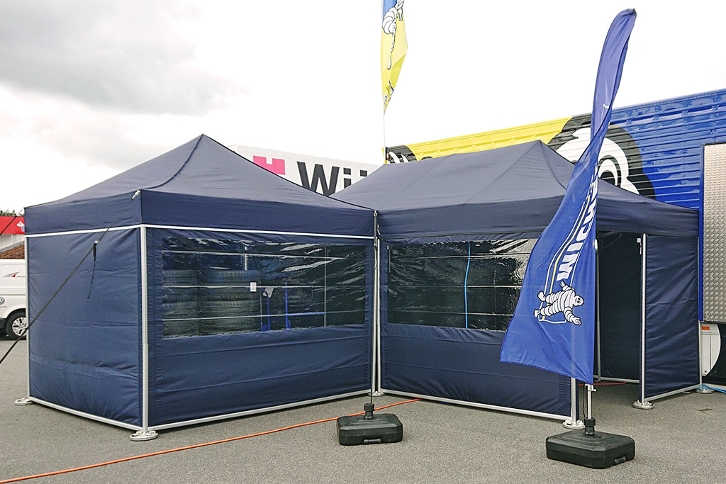 A racing tent with side walls is used as tire storage.