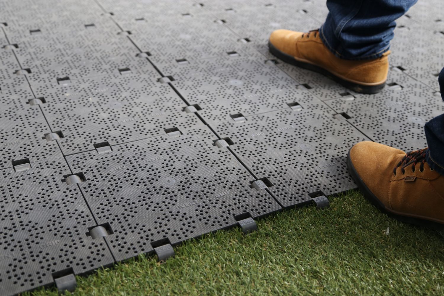 A man stepping on Pro-Tent floor panels laid on grass.