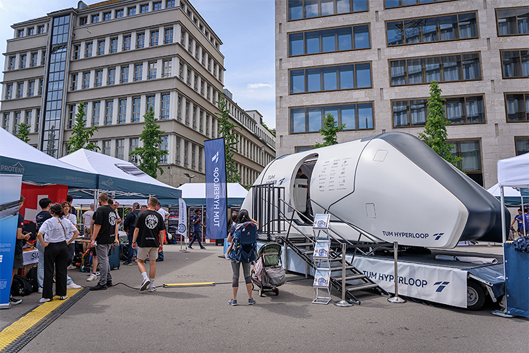 Ein Hyperloop-Pod steht neben einem Gelände voller Pro-Tent Faltzelte.