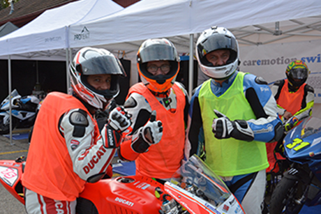 Three motorcycle racers pose in front of a Pro-Tent folding tent.