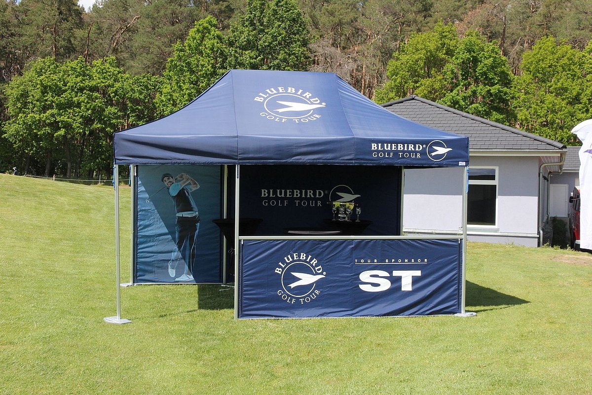 Der blaue Pro-Tent 5000 Faltpavillon von FairwaySports hat mehrere aufgedruckte Logos.