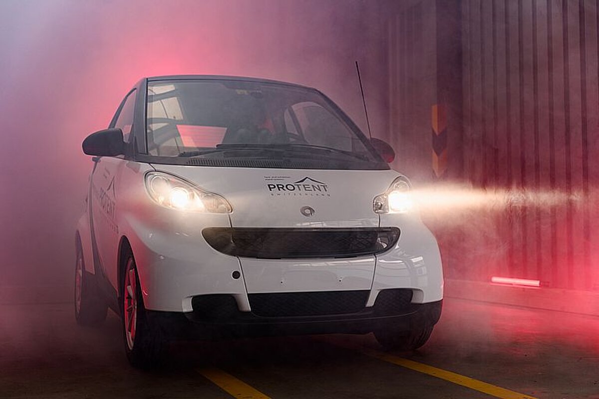 A Smart Fortwo challenging our Pro-Tent 5000 folding tent. A Smart Fortwo is staged in an industrial hall with red light and fog.