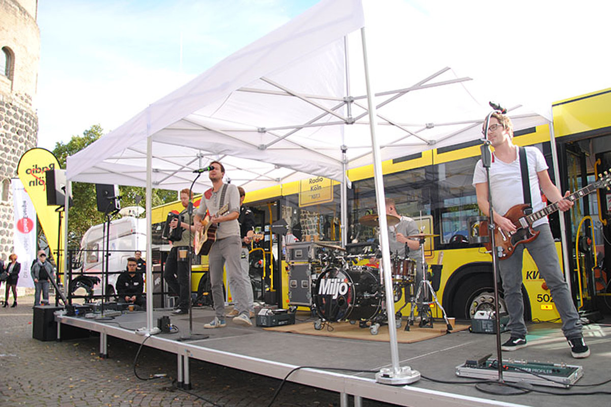 Die Band Miiljö spielt unter einem Pro-Tent Faltzelt vor einem Bus in Köln. 