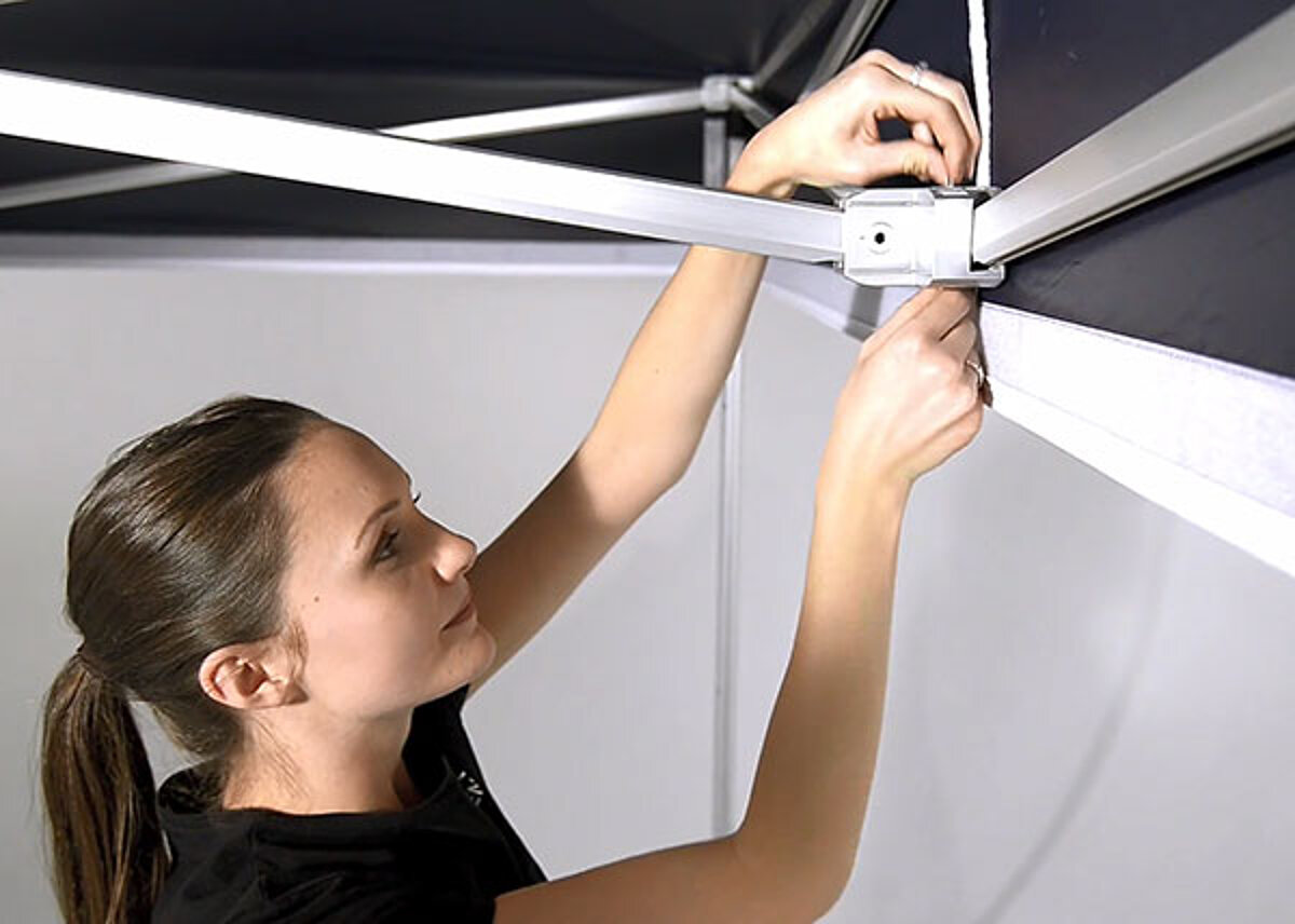A woman secures the tent roof with a loop.