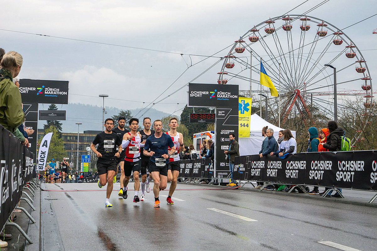 Eine Gruppe Läufer läuft am Ziel des Zürich Marathons ein.