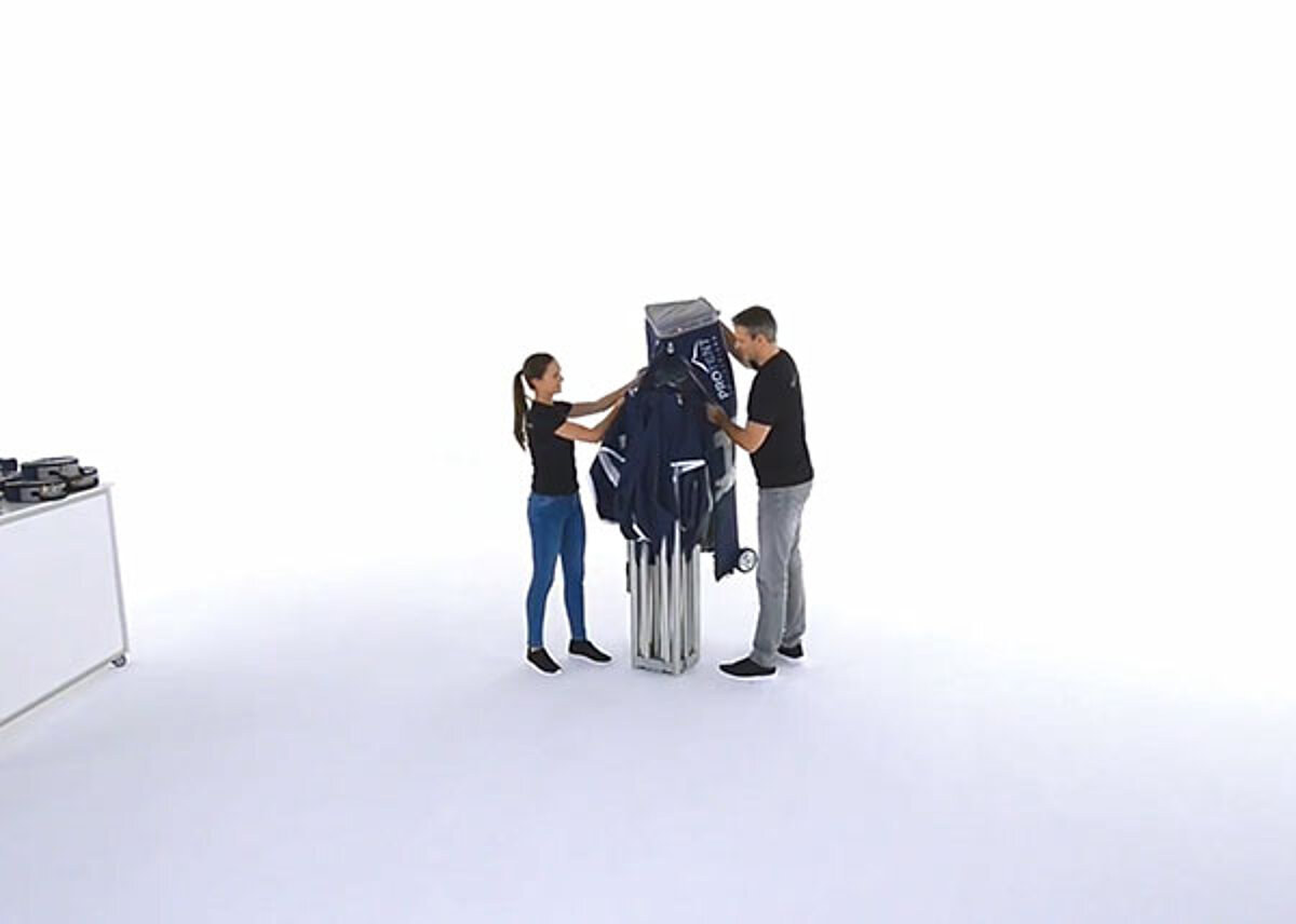 Two persons remove the transport bag from their folding tent.
