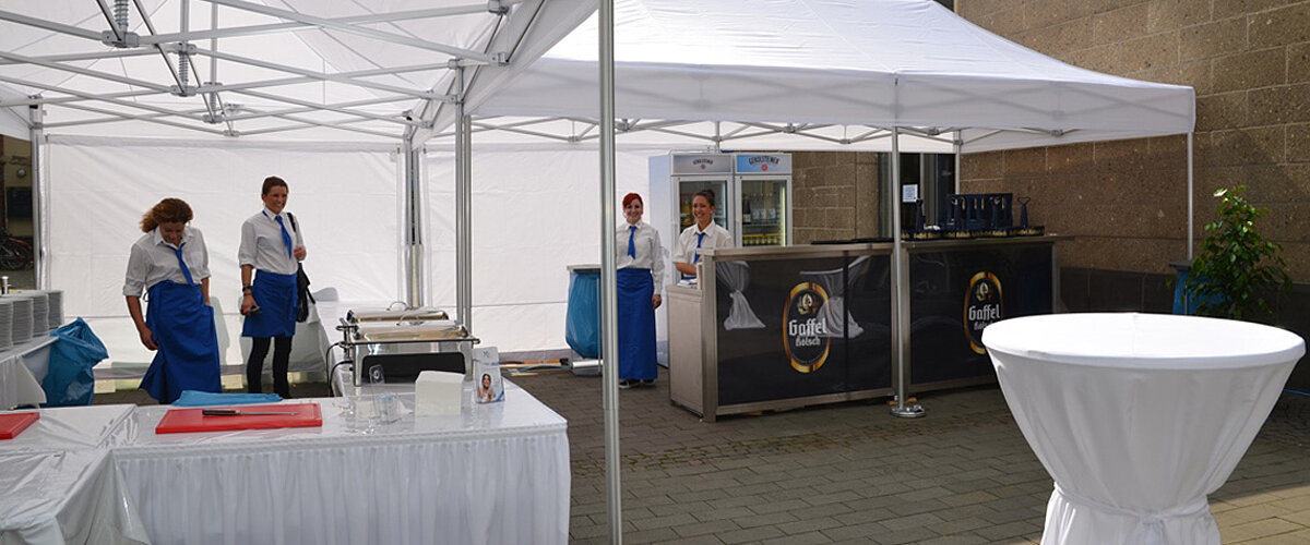 Ein Catering-Unternehmen hat sein Buffet bei einem Event unter zwei Faltzelten aufgebaut.
