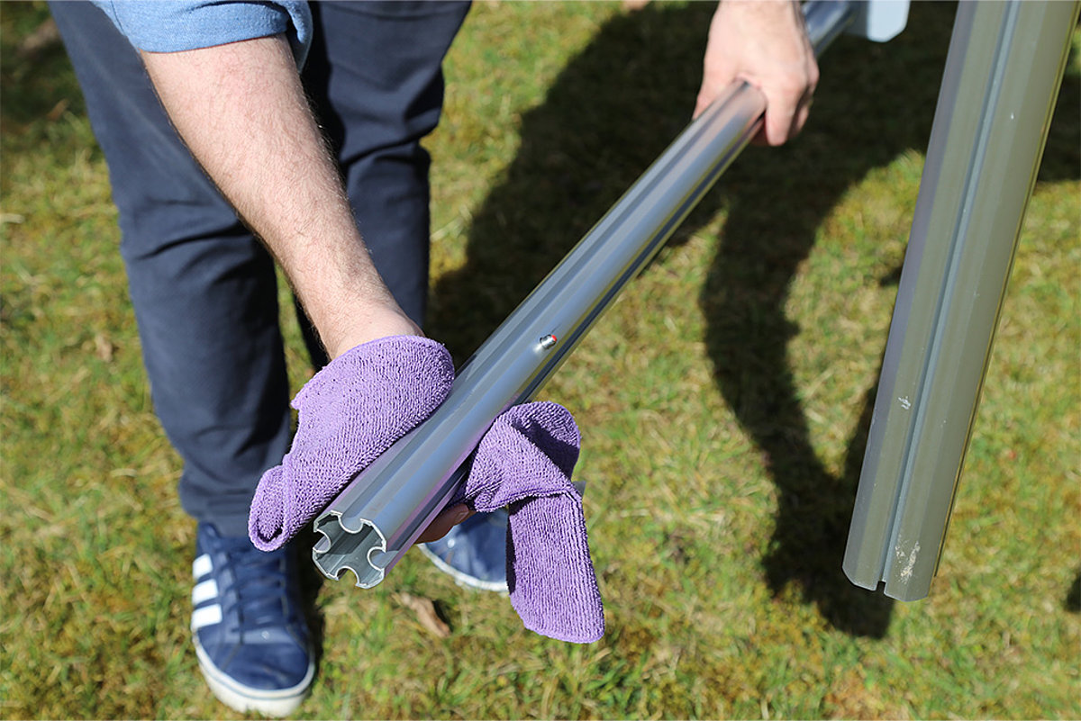 One of the legs of a Pro-Tent folding tent is cleaned with a cloth.