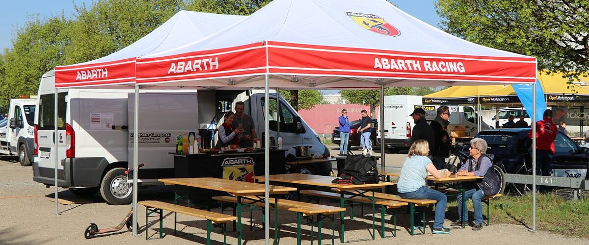 Plusieurs personnes sont assises sur des bancs sous un pavillon pliable.