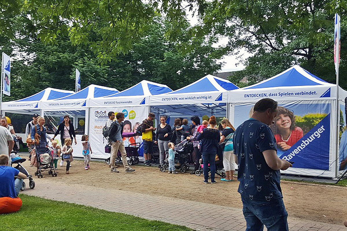 Ravensburger uses several Pro-Tent folding tents at an outdoor event for children.