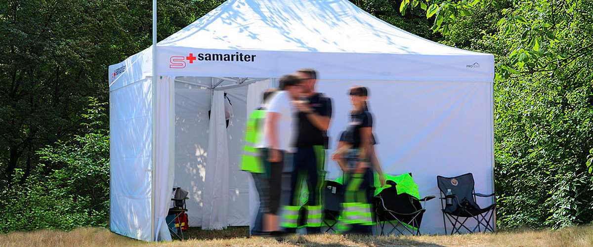 Die Schweizer Samariter arbeiten vor einem Einsatzzelt mit Innenkabine von Pro-Tent.