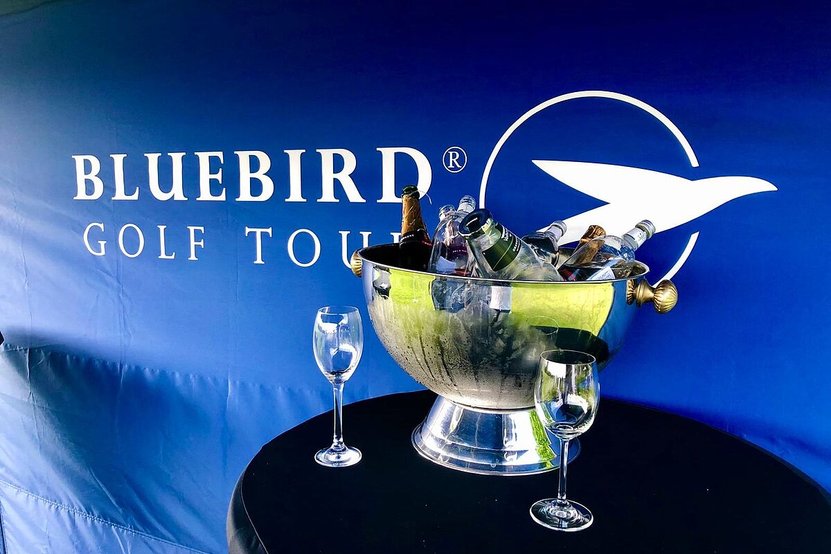 The back walls are perfect for branding. A champagne cooler and two glasses on a table in the FairwaySports folding golf tent.