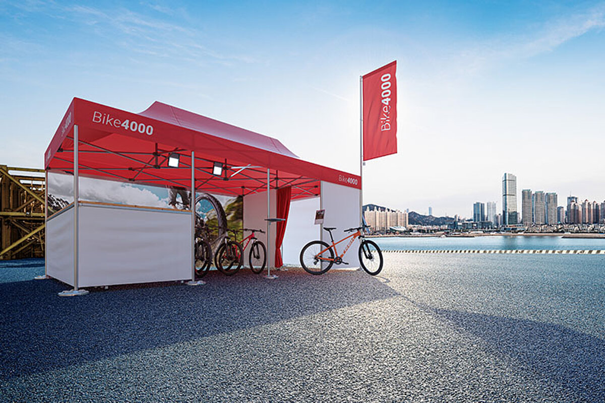 Un stand de publicitate pentru compania Bike4000 este asamblat lângă un port.