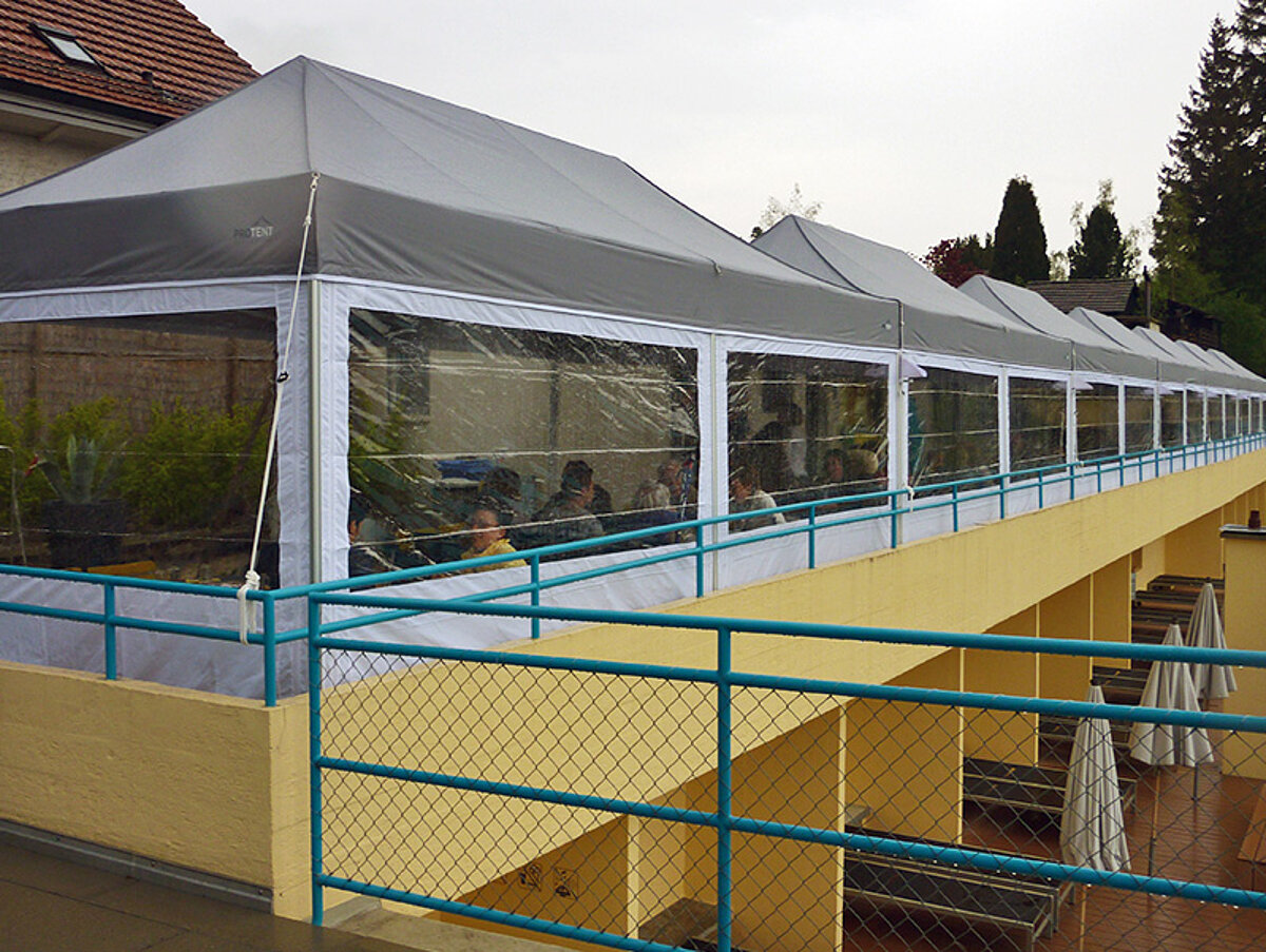 Molti gazebo catering impermeabili in uso per ristorazione all’aperto sotto la pioggia.