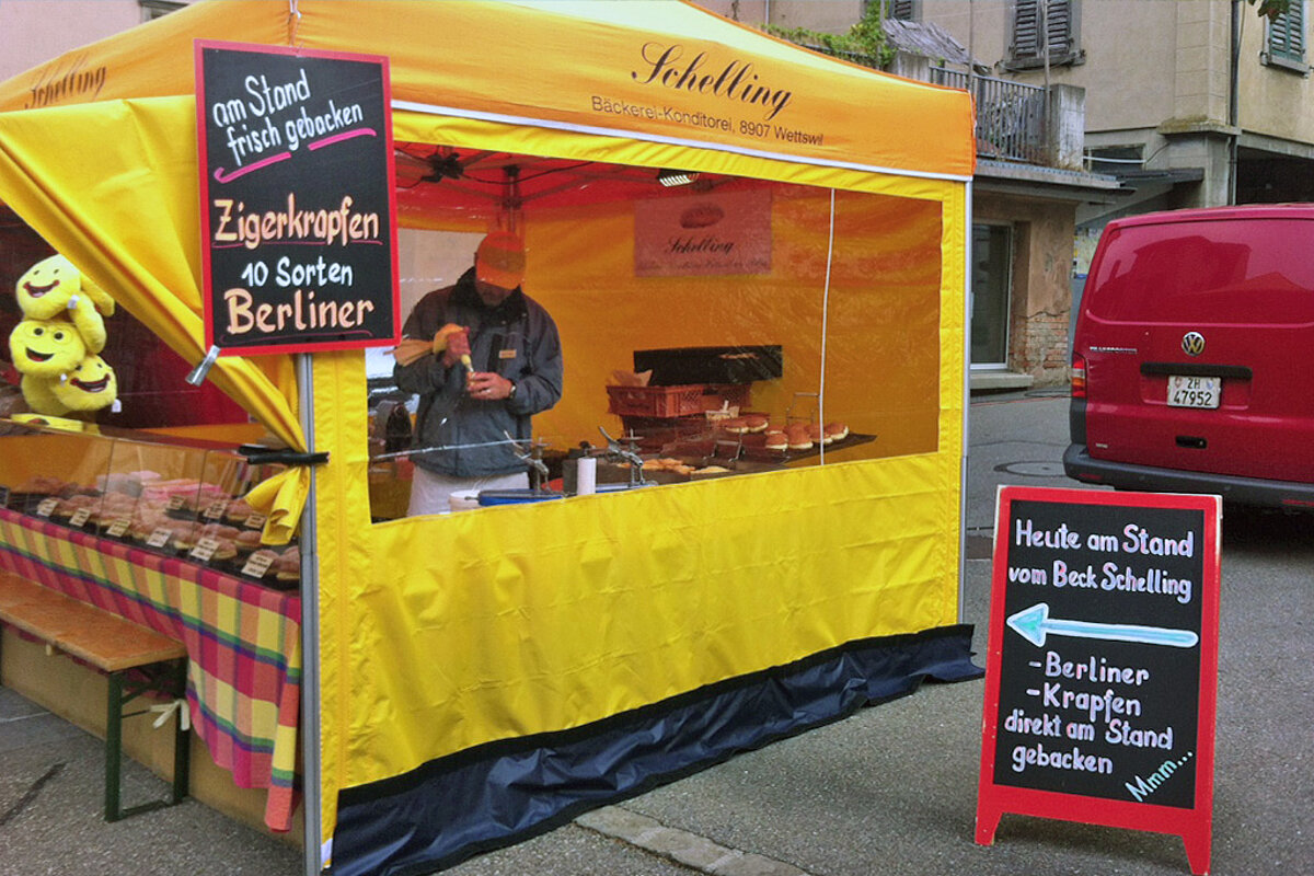 Ein Bäcker nutzt ein Street Food Zelt, um auf einem Markt frische Berliner und Krapfen zu backen.