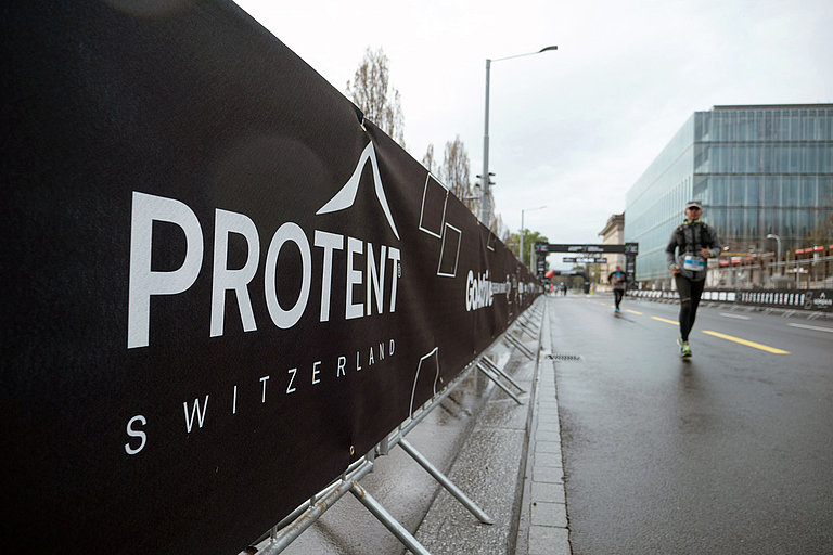 Pro-Tent perimeter advertising along the marathon course with athletes running.