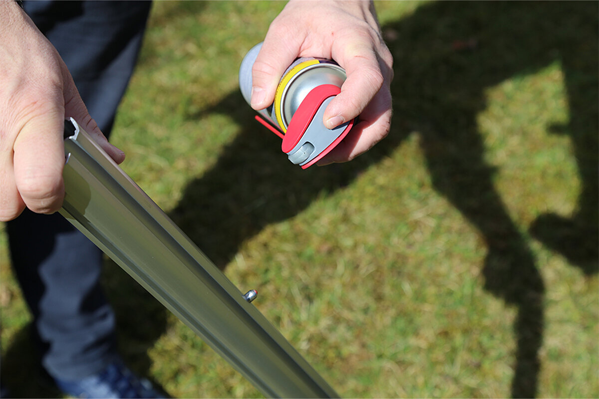 Ein Standbein eines Pro-Tent Faltzelts wird mit Silikonspray eingesprüht. 
