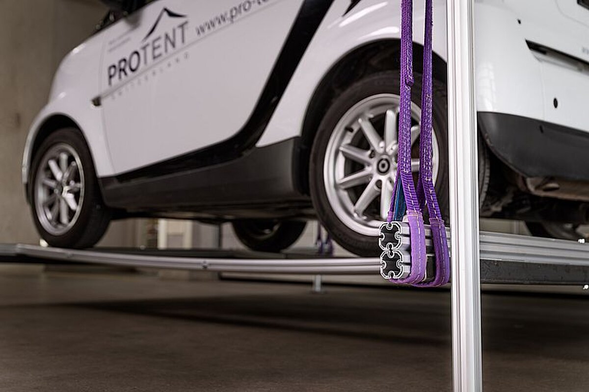 The Smart was parked on Pro-Tent profile poles, which were suspended in the folding tent. A Smart standing on profile poles that have been attached by straps in a Pro-Tent folding tent.